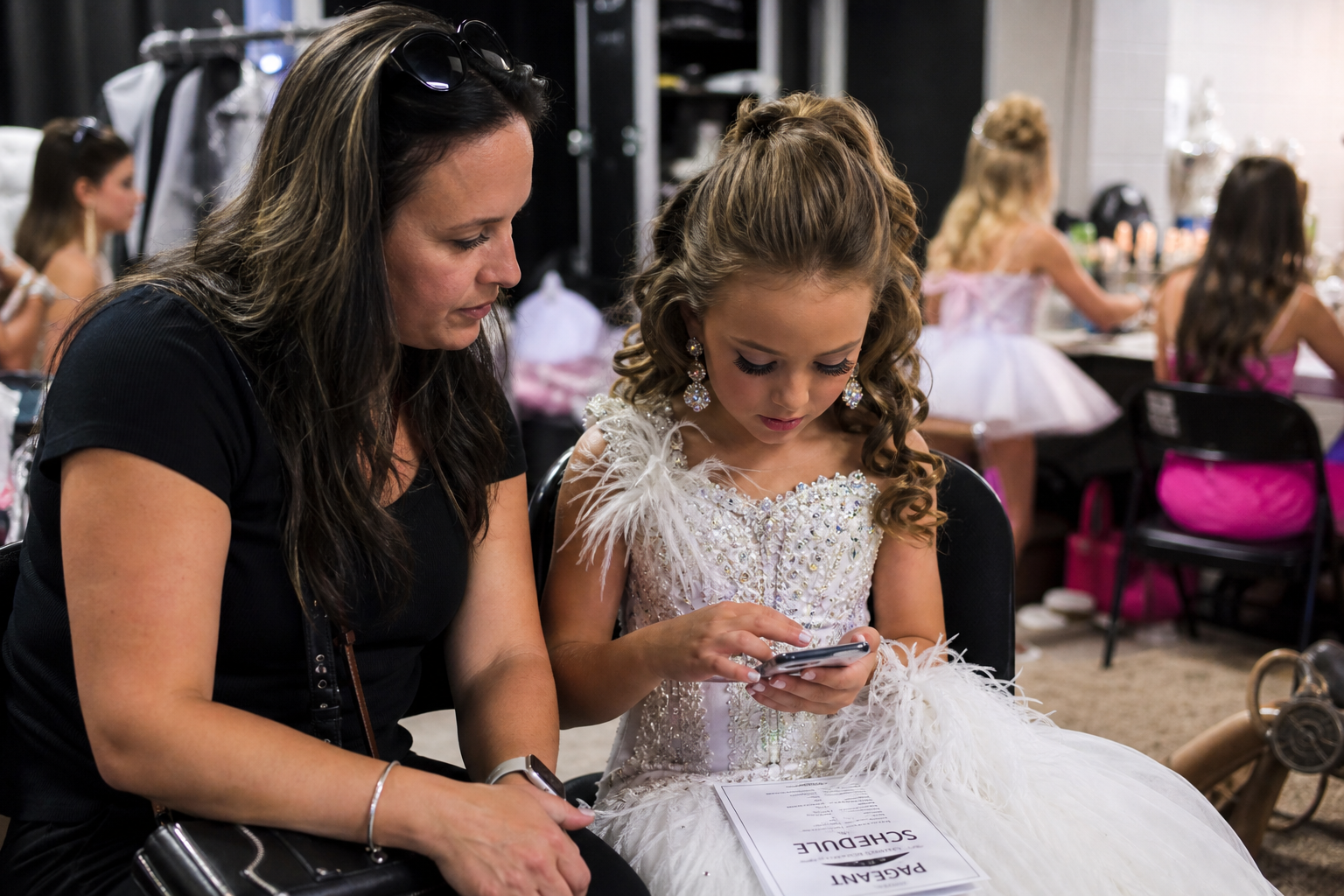A guardian and young contestant reviewing information together in a supervised backstage setting